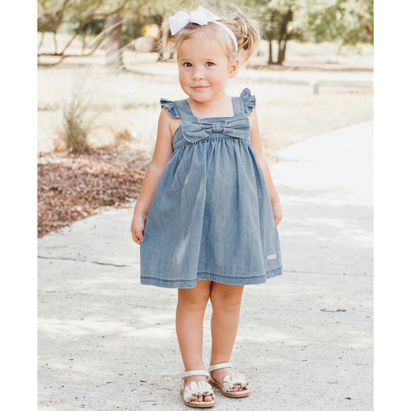 Model Wearing Rufflebutts & Ruggedbutts Girls Light Wash Denim Flutter Bow Woven Dress 